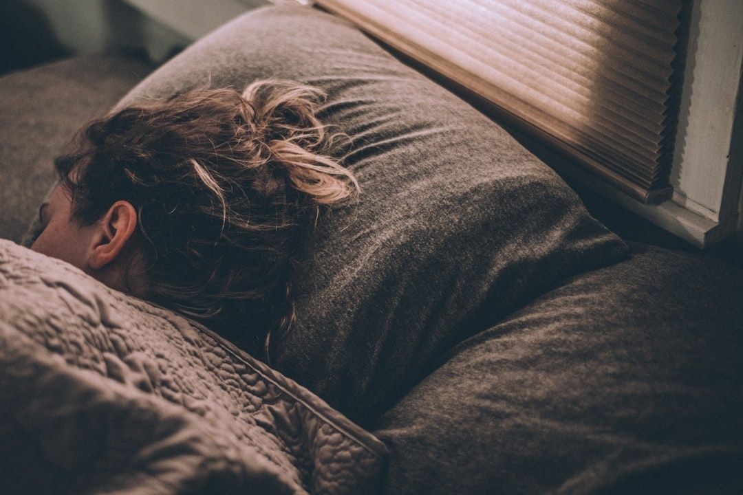 Sovande person under ett täcke i sängen vid ett fönster